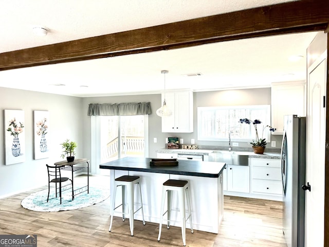 kitchen with sink, stainless steel refrigerator, white cabinets, and a center island