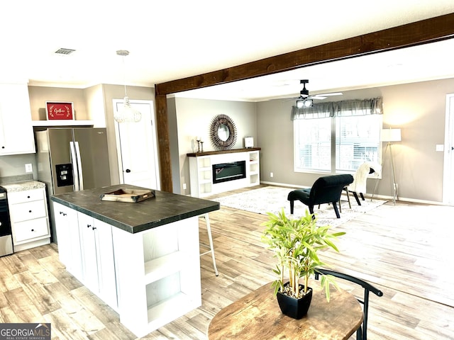 kitchen with light hardwood / wood-style flooring, white cabinetry, beam ceiling, a kitchen island, and decorative light fixtures