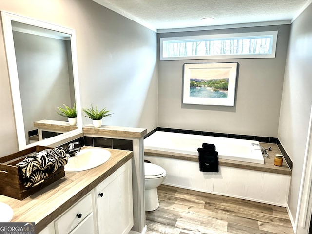 bathroom with hardwood / wood-style floors, vanity, a bath, a textured ceiling, and toilet