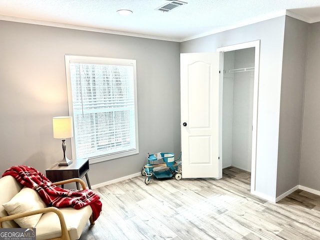 living area with crown molding, plenty of natural light, and light hardwood / wood-style flooring