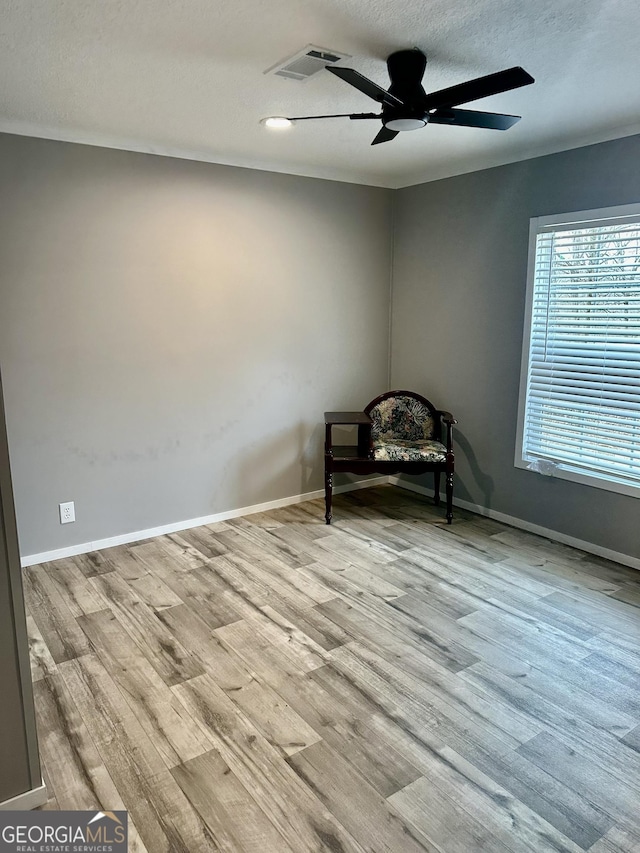 unfurnished room with ceiling fan, a textured ceiling, and light hardwood / wood-style floors