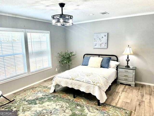 bedroom with crown molding, wood-type flooring, and a textured ceiling