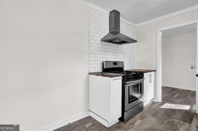 kitchen with wood walls, range hood, decorative backsplash, and stainless steel gas range