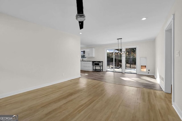 unfurnished living room with an inviting chandelier and light hardwood / wood-style floors