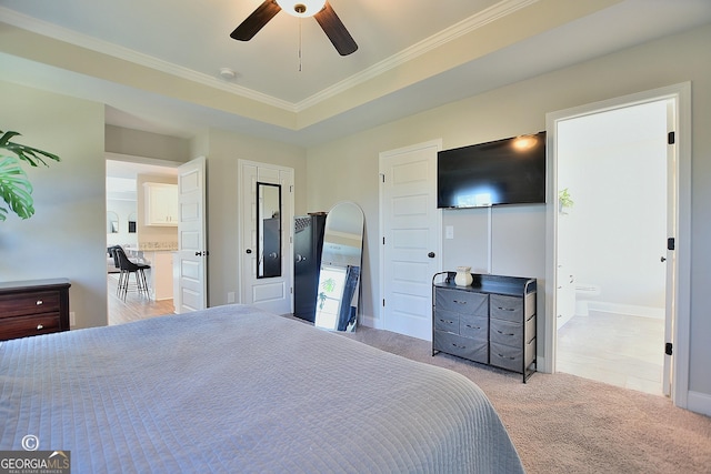 bedroom featuring a raised ceiling, ornamental molding, light carpet, and ensuite bath