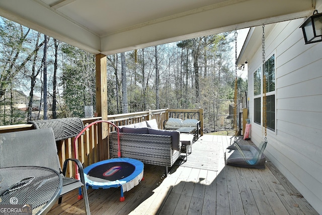 wooden terrace with area for grilling and an outdoor living space