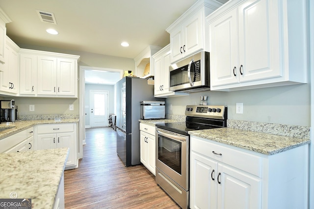 kitchen with stainless steel appliances, dark wood-type flooring, white cabinets, and light stone counters