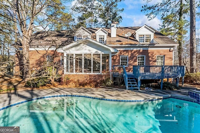 rear view of property featuring a sunroom and a swimming pool side deck