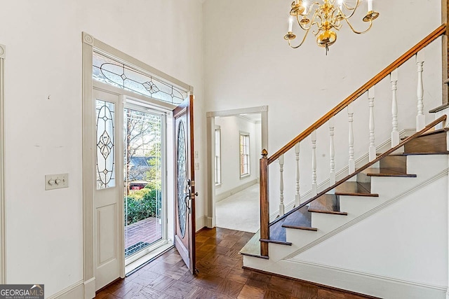 entryway with a high ceiling, an inviting chandelier, and dark parquet floors