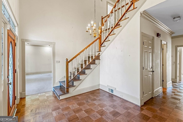 entrance foyer featuring dark parquet floors, ornamental molding, a chandelier, and a high ceiling