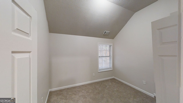 carpeted spare room with vaulted ceiling and a textured ceiling