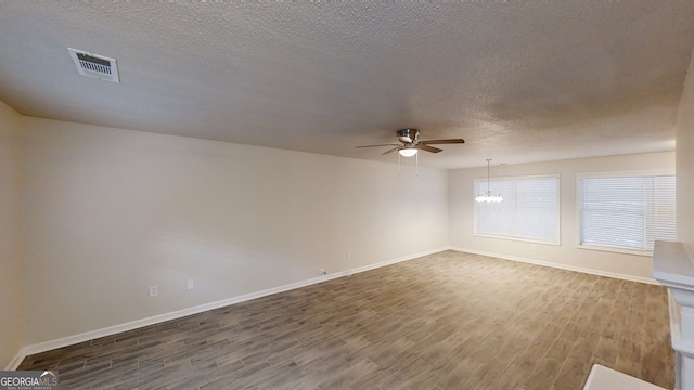 empty room featuring wood-type flooring, ceiling fan with notable chandelier, and a textured ceiling