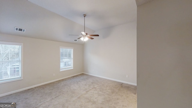 empty room featuring lofted ceiling, ceiling fan, a wealth of natural light, and light carpet