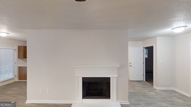 unfurnished living room with light hardwood / wood-style flooring and a textured ceiling