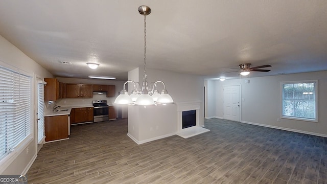 kitchen featuring hanging light fixtures, wood-type flooring, ceiling fan with notable chandelier, and stainless steel electric range