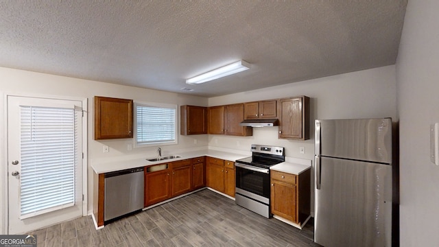 kitchen with stainless steel appliances, sink, hardwood / wood-style floors, and a textured ceiling