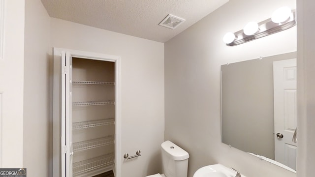 bathroom featuring a textured ceiling and toilet