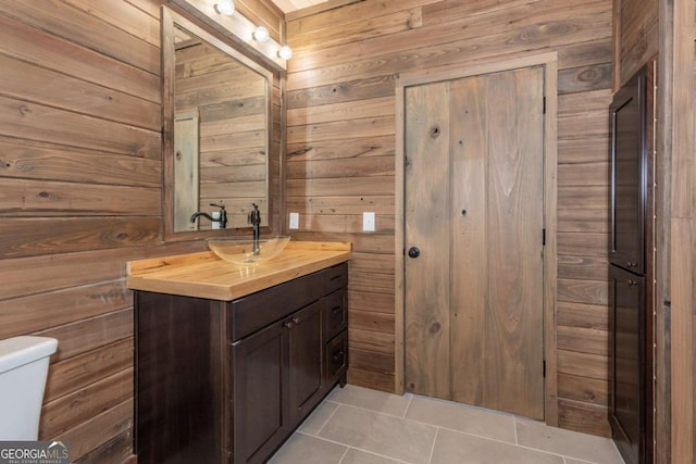 bathroom featuring tile patterned floors, toilet, vanity, and wood walls