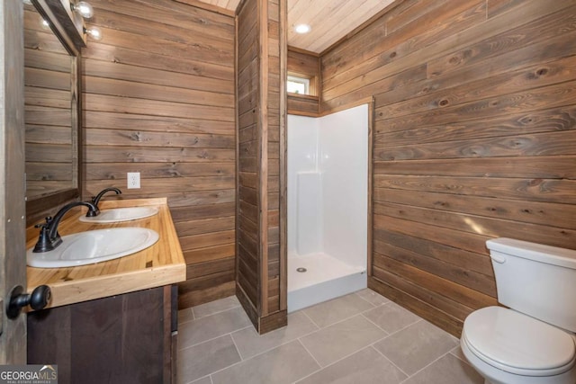 bathroom featuring toilet, a shower, vanity, wooden walls, and tile patterned flooring