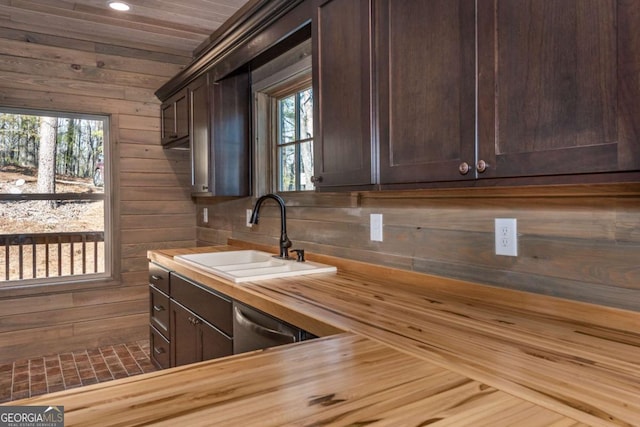 kitchen with wooden counters, sink, dark brown cabinets, and wood walls