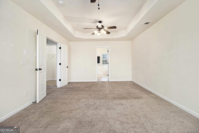 unfurnished room featuring ceiling fan, a raised ceiling, and carpet