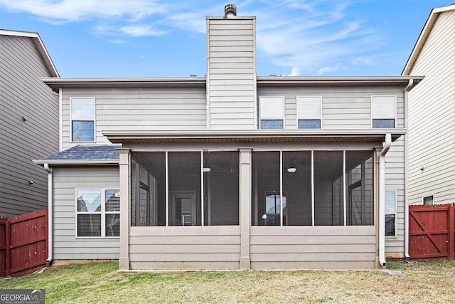 back of house featuring a yard and a sunroom