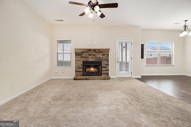 unfurnished living room with ceiling fan, a fireplace, and carpet floors