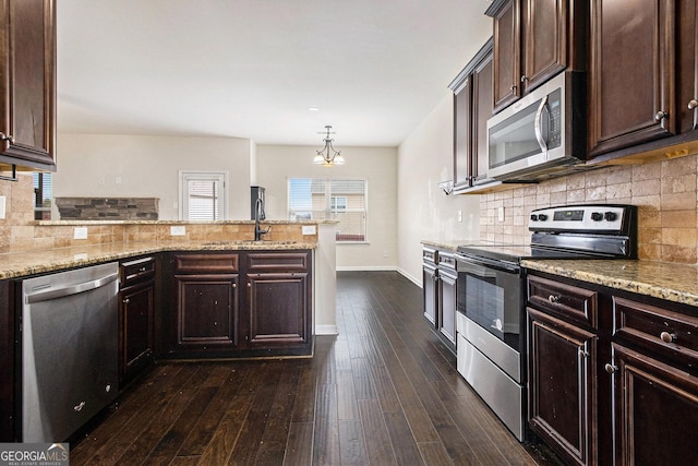 kitchen with light stone counters, decorative light fixtures, dark hardwood / wood-style floors, stainless steel appliances, and backsplash