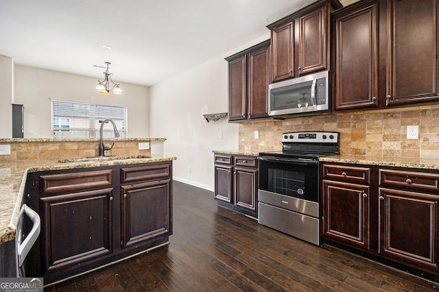 kitchen featuring sink, decorative light fixtures, dark brown cabinets, stainless steel appliances, and decorative backsplash