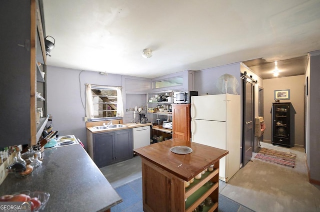 kitchen with a barn door, sink, concrete floors, and white appliances