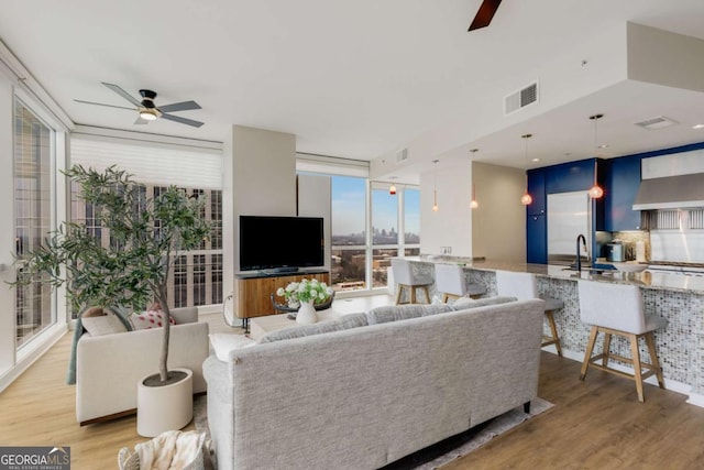 living room featuring ceiling fan, light wood finished floors, and visible vents