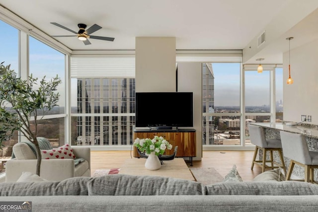 living area featuring expansive windows, a ceiling fan, and plenty of natural light