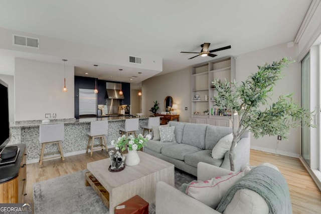 living area with baseboards, ceiling fan, light wood-type flooring, and visible vents