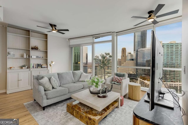 living room with a ceiling fan, plenty of natural light, and light wood-style flooring