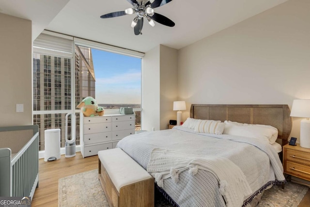 bedroom featuring expansive windows, a ceiling fan, and wood finished floors