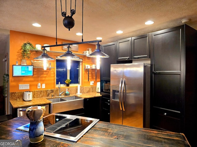 kitchen featuring a sink, decorative light fixtures, a textured ceiling, recessed lighting, and appliances with stainless steel finishes