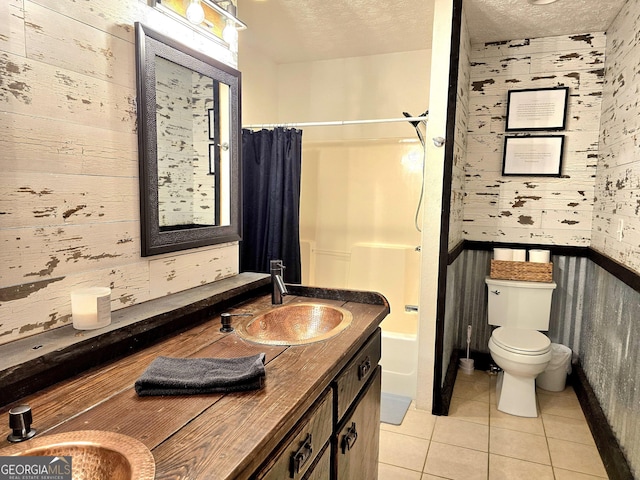 bathroom featuring toilet, shower / tub combo with curtain, a sink, a textured ceiling, and tile patterned flooring