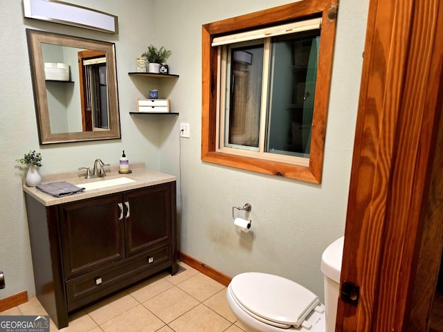 half bathroom with vanity, tile patterned floors, toilet, and baseboards