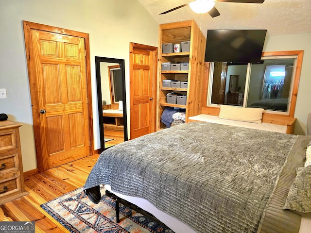 bedroom featuring a textured ceiling, lofted ceiling, wood finished floors, and ceiling fan