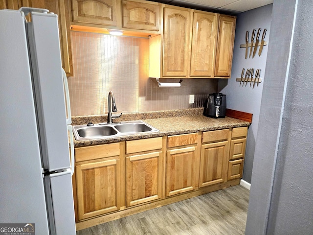 kitchen featuring a sink, light wood-type flooring, and freestanding refrigerator