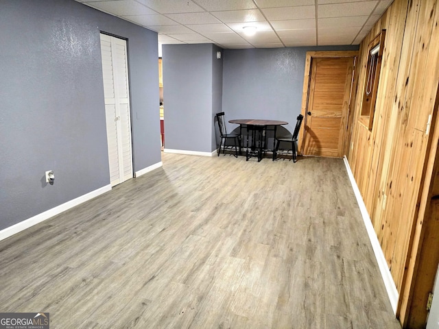 interior space with a drop ceiling, baseboards, and wood finished floors