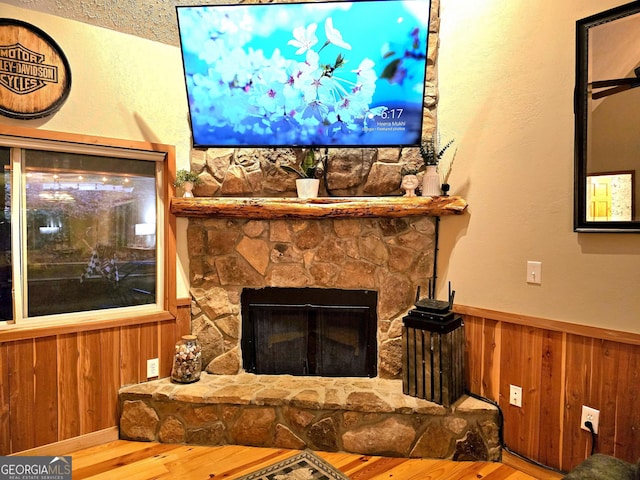 living area with wood finished floors, a fireplace, wood walls, and wainscoting