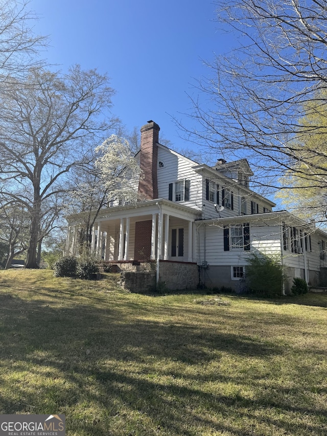 exterior space featuring a chimney, a yard, and a porch