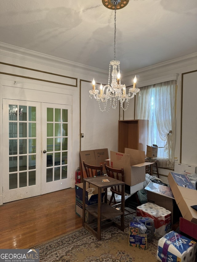 dining area with french doors, ornamental molding, wood finished floors, and a chandelier