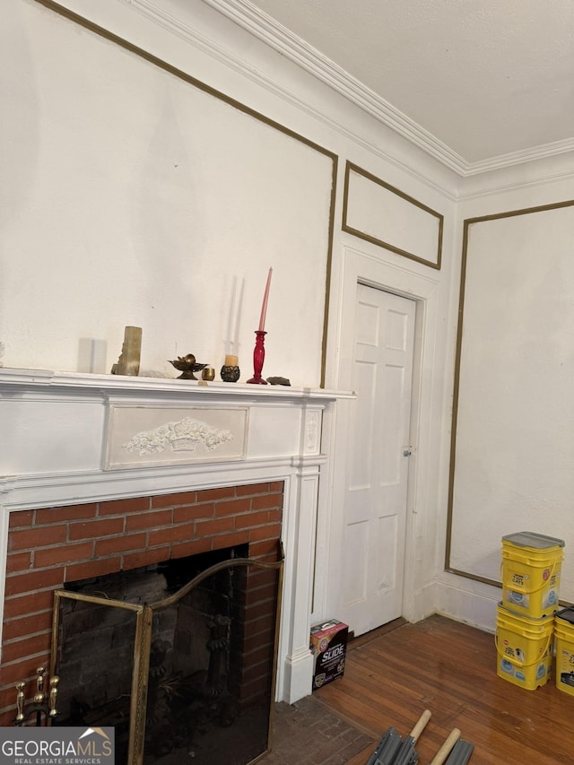 details featuring ornamental molding, a brick fireplace, and wood finished floors