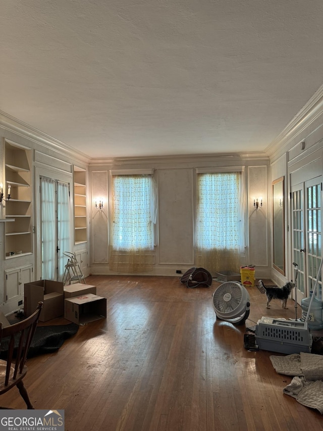 living room with crown molding, wood-type flooring, and a decorative wall