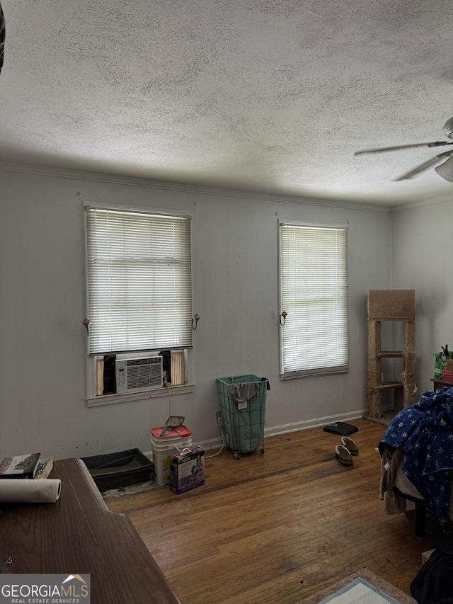 bedroom with a textured ceiling, wood finished floors, and multiple windows