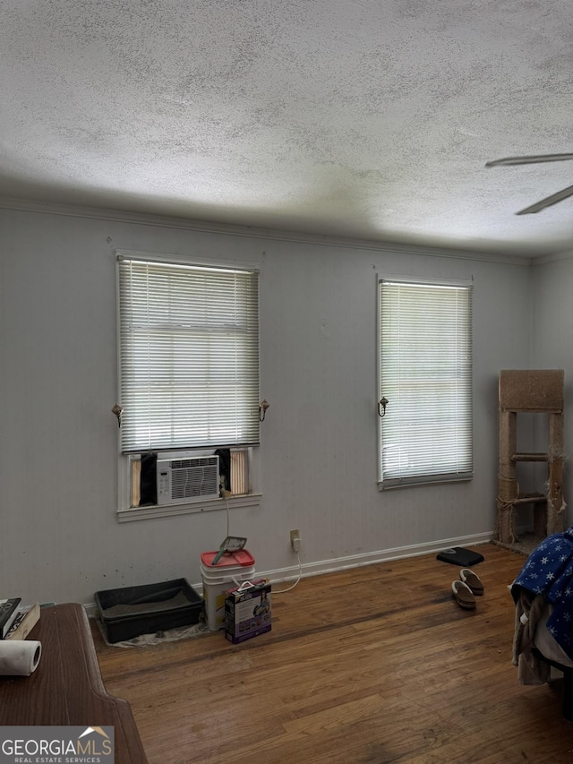 interior space featuring wood finished floors, a textured ceiling, a healthy amount of sunlight, and cooling unit