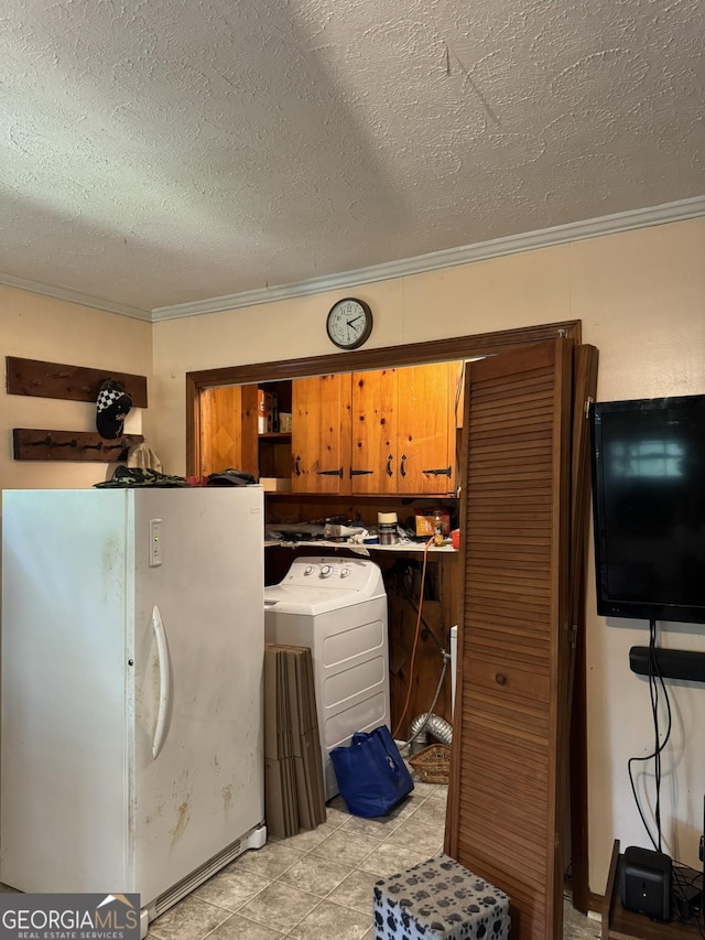 kitchen featuring freestanding refrigerator, ornamental molding, washer / clothes dryer, a textured ceiling, and brown cabinets