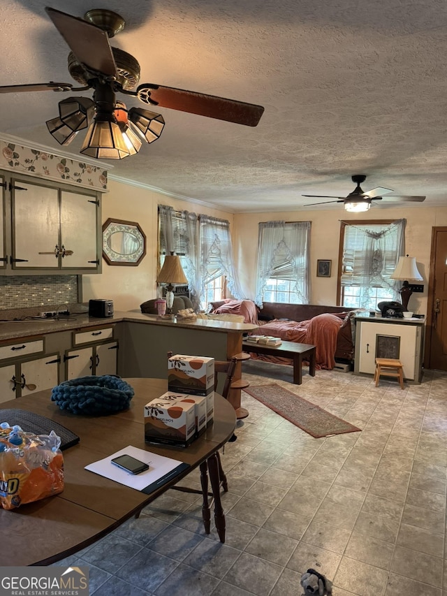 living area featuring a ceiling fan, a textured ceiling, ornamental molding, and light tile patterned floors